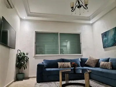 a living room with a blue couch and a window at Central Park in Mohammedia