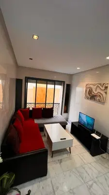 a living room with a red couch and a table at Beautiful appartement with pool view in Mohammedia