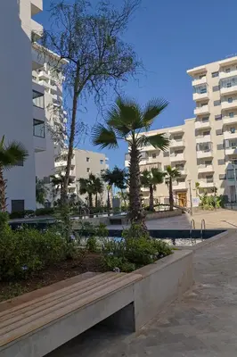 a bench in a park with palm trees and buildings at Cozy Modern Studio Near Zenâta Beach in Casablanca