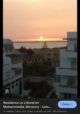 a sunset over a city with buildings and the ocean at Resedence lettoral in Mohammedia
