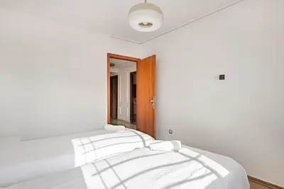 a white bedroom with a bed with white sheets at Agdal Train Station Modern&Stylish Apartments in Rabat