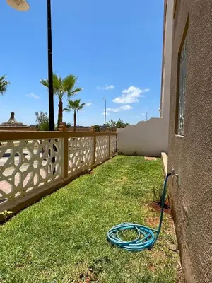 a hose laying on the grass next to a fence at Saad in Mohammedia