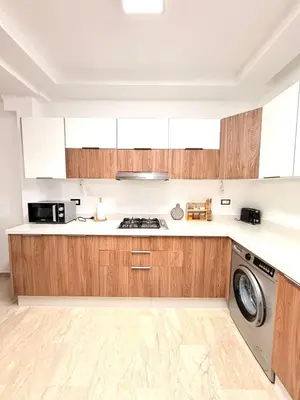 a kitchen with wooden cabinets and a washing machine at Charmante maison de vacances proche de la plage à quelques minutes de Rabat in Temara