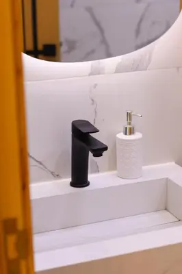 a bathroom sink with a black faucet and a toilet paper holder at Le Nour- 2 modern bedrooms Luxury and Comfort in Bouznika