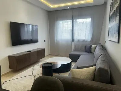 a living room with a couch and a tv at Appartement 1BR Prestige & Confort à Hay Riad in Rabat