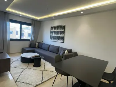 a living room with a blue couch and a table at Appartement 1BR Prestige & Confort à Hay Riad in Rabat