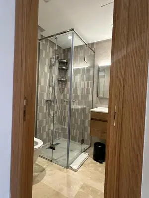 a bathroom with a shower with a toilet and a sink at Appartement 1BR Prestige & Confort à Hay Riad in Rabat