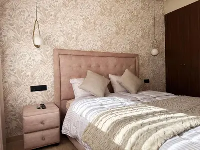 a bedroom with a large bed and a night stand at Zenata Luxury Stay in Aïn Harrouda