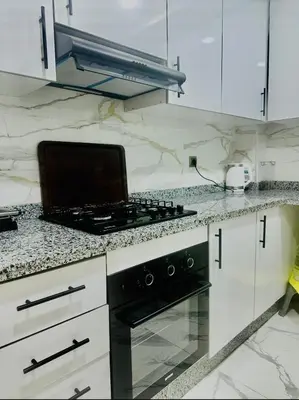 a kitchen with white cabinets and a stove top oven at Najia Blue Pearl in Sidi Rahal