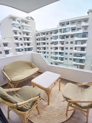 a balcony with two chairs and a table and chairs at Cozy 2-bedroom apartment, pool view with beach access a Zenata City Eco Casablanca in Oulad Akkou