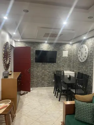 a dining room with a table and a clock on a wall at relaxing apartment in Bouznika in Bouznika