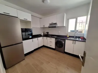a kitchen with white cabinets and a washer and dryer at T3 Moderne proche Ocean in Rabat