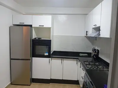 a kitchen with white cabinets and a stove top oven at T3 Moderne proche Ocean in Rabat