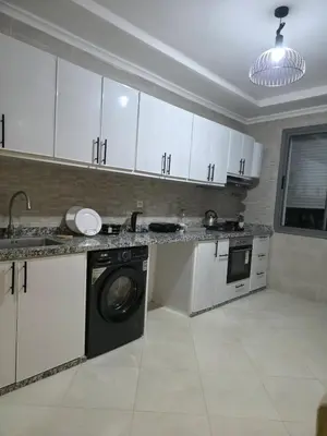 a kitchen with white cabinets and a washing machine at appartement luxe dt5 in Mohammedia