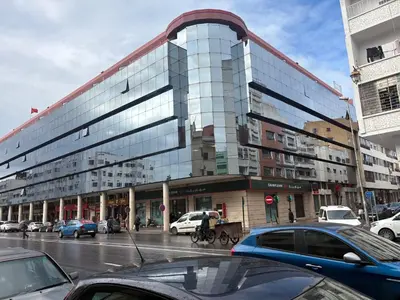 a large glass building on a city street with cars at Appartamento di lusso nel cuore di Rabat in Rabat