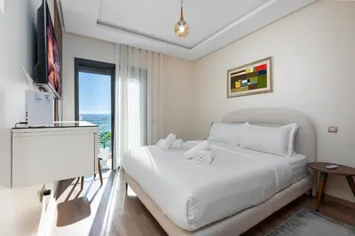 a white bedroom with a bed and a window at Luxury 2BR Pearl of Agdal Near Agdal Train Station in Rabat