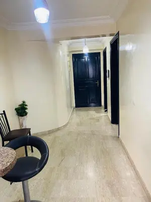 a hallway with a black door and a chair at Résidence TPM in Casablanca