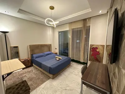a bedroom with a bed and a table and a chair at Hay Riad Sunset Studio Stadium View , 5 mind a pied stade moulay abdelah in Rabat