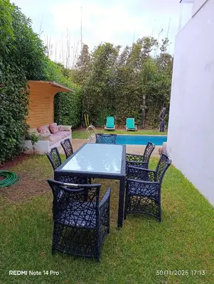 a table and chairs in a yard with a pool at Océane palm in Casablanca