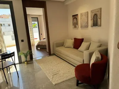 a living room with a couch and a red chair at Modern, Fully Equipped Studio Close to Mohamed 5 Stadium - Maarif in Casablanca