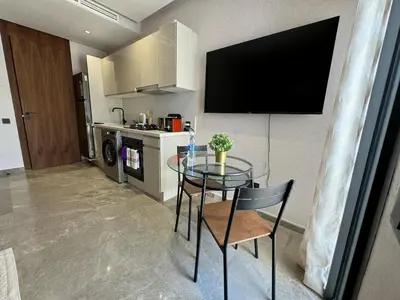 a kitchen with a glass table with a television on the wall at Modern, Fully Equipped Studio Close to Mohamed 5 Stadium - Maarif in Casablanca