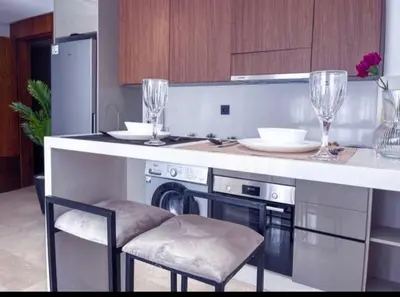 a kitchen with a counter with chairs and wine glasses at Sleek Modern Studio with Plenty of Light in Casablanca