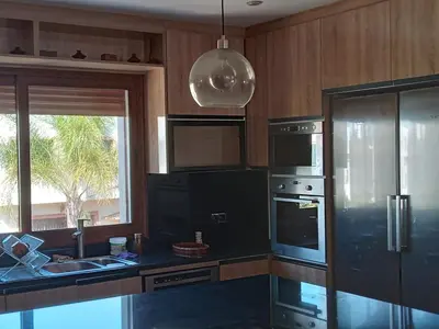 a kitchen with black appliances and a sink and a window at Villa avec piscine proche de la mer in Mohammedia