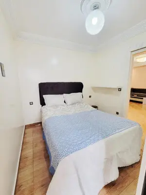 a white bedroom with a bed with a blue comforter at 7 min to beach luxury apartment Dar Bouazza in Casablanca