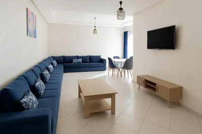 a living room with a blue couch and a table at Évasion Marine & piscine 3 chambres in Bouznika