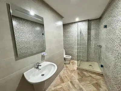 a bathroom with a sink and a toilet and a mirror at Appartement moderne aux perles de temara in Temara