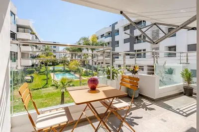 a balcony with a wooden table and chairs and a building at La perle de Harhoura Piscine-Océan -Terrain Rabat in Temara