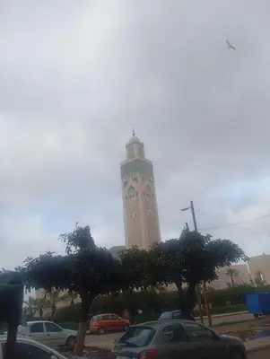 a tall clock tower with cars parked in a parking lot at Bd les iris in Casablanca