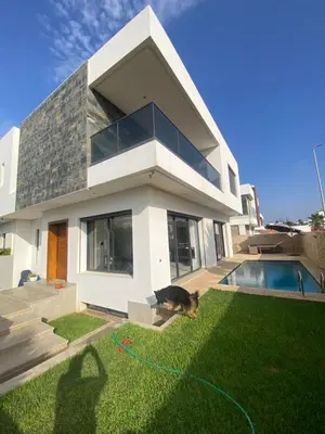a cat is sitting on the grass in front of a house at Villa luxueuse plage des princesses in Rabat