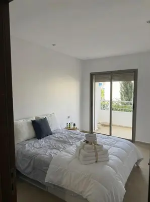 a bedroom with a large white bed with a window at 2BR Beach Apt, Pool, Luxury place in Mansouria