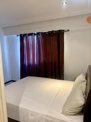 a bed in a room with a window with a curtain at Apartment in Agdal, 3-min walk from Arribat Center in Rabat