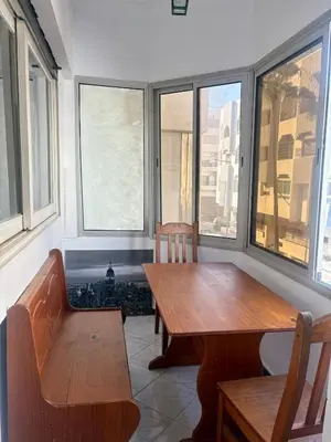 a dining room with a table and chairs and windows at Apartment in Agdal, 3-min walk from Arribat Center in Rabat