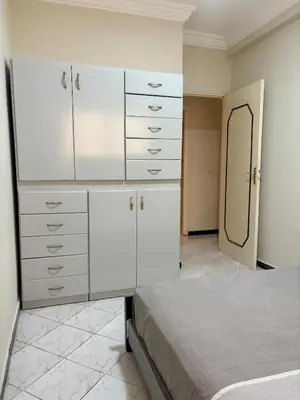 a bedroom with white dressers and a bed with a mirror at Apartment in Agdal, 3-min walk from Arribat Center in Rabat