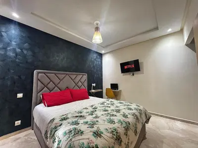 a bedroom with a bed with a red pillow at Appartement Bouznika POOL & BEACH in Bouznika