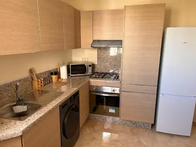 a kitchen with a white refrigerator and a sink at Appartement Bouznika POOL & BEACH in Bouznika