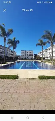 a large swimming pool with palm trees and buildings at well-equipped apartment in Mansouria