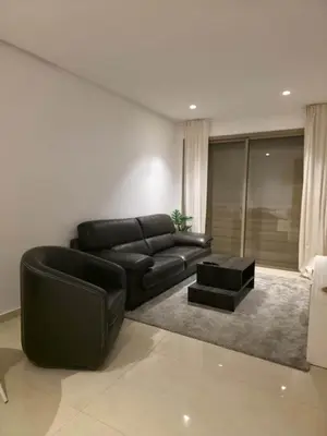 a living room with a black leather couch and a table at super studio in Aïn Harrouda