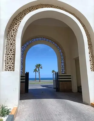 an archway leading to the beach with a palm tree at Appartement vue sur mer 3 chambres in Rabat