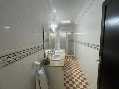 a white bathroom with two sinks and a mirror at Maison Bord de Mer Skhirate in Skhirat