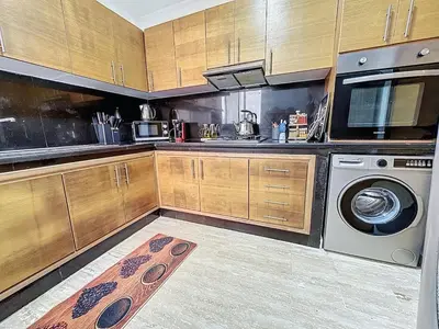 a kitchen with wooden cabinets and a washer and dryer at Appartement Typique Marocain in Oulad Akkou