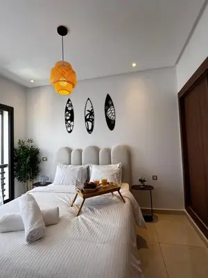 a bedroom with a large bed with a table on it at Cozy & Chill à 30min terrain de foot Netflix, AC pool & beach 2 min, in Bouznika