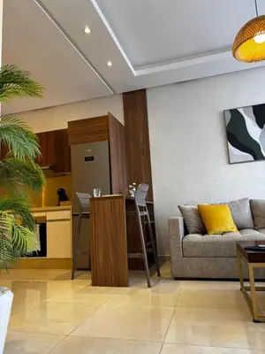 a living room with a couch and a kitchen at Cozy & Chill à 30min terrain de foot Netflix, AC pool & beach 2 min, in Bouznika