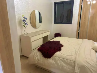 a bedroom with a white bed and a mirror at Appartement chic a 5 mins de la plage in El Harhoura