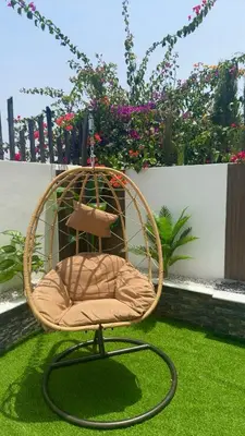 a wicker chair sitting on the grass in a garden at Appartement chic a 5 mins de la plage in El Harhoura