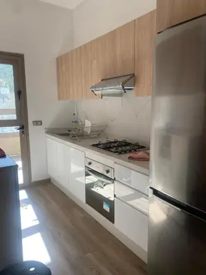 a kitchen with a stove and a refrigerator at New ground floor apartment - Large terrace direct access to pool in Bouznika