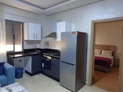 a small kitchen with a refrigerator and a bed at Apartment kamal park F1 in Mohammedia
